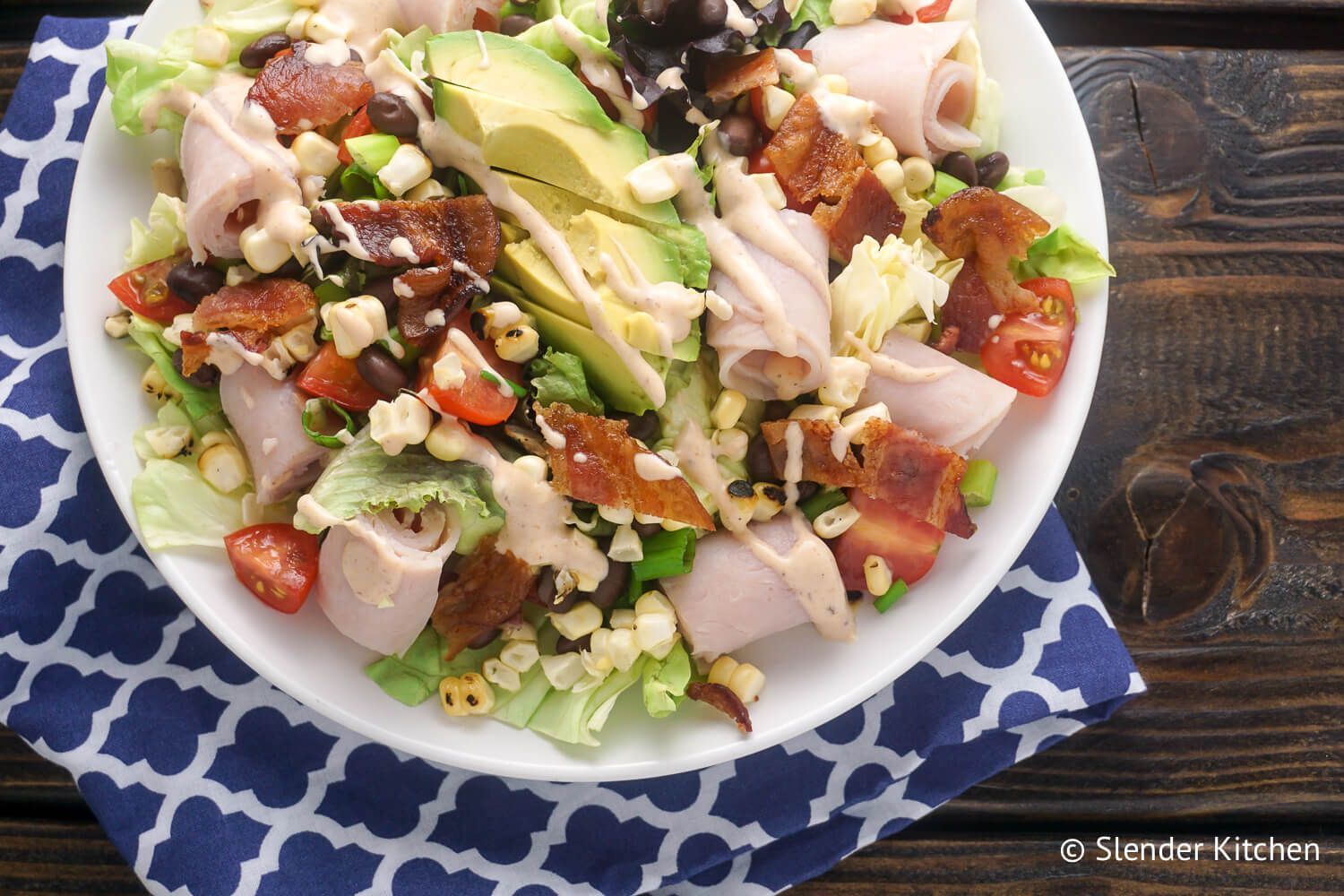 Southwestern Turkey BLTA Salad Southwestern Turkey and bacon salad with corn and black beans in a bowl.