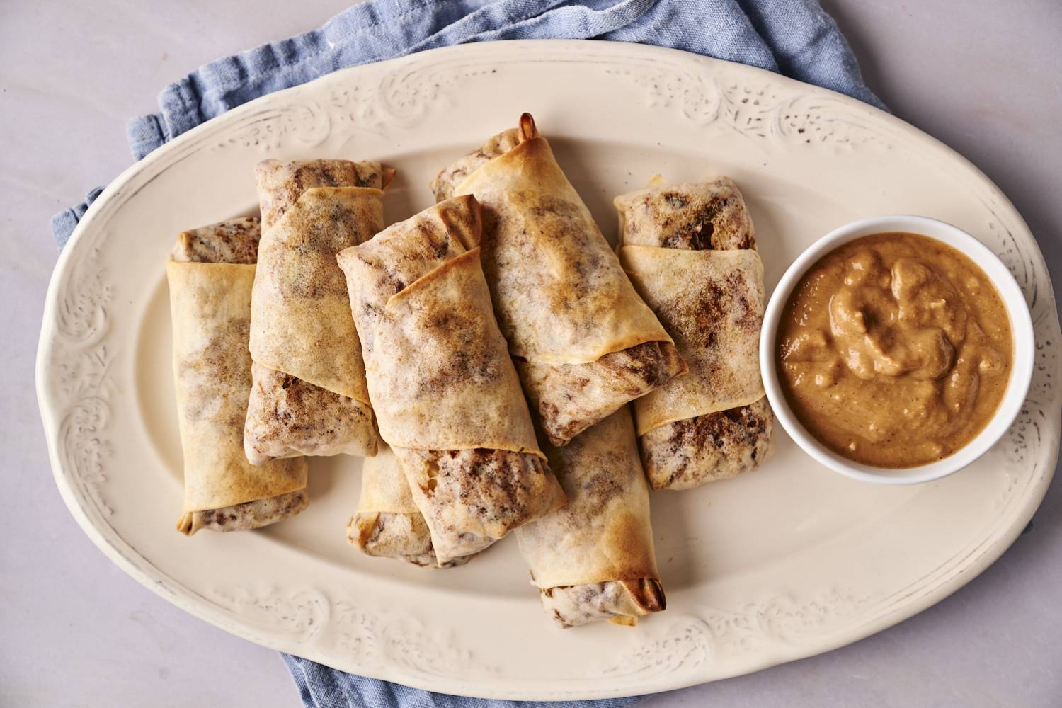 Vegetable Egg Rolls A plate of four vegetable egg rolls with a side of dipping sauce.
