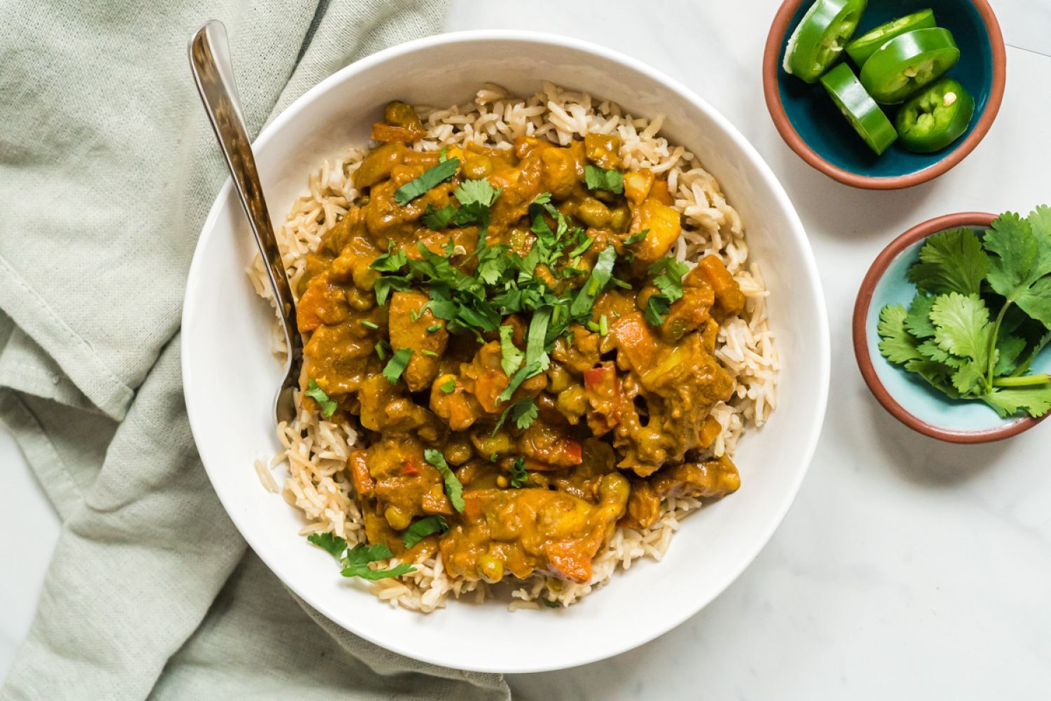 Vegetable Korma Vegetable korma with potatoes and carrots in a creamy tomato coconut curry sauce on a plate with rice and cilantro.