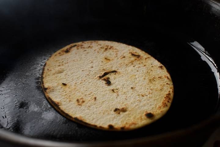 The tortillas are lightly fried in a pan.