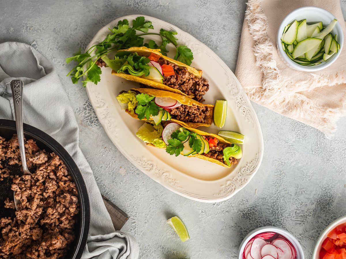 Ground beef tacos with ancho chili seasoning served in baked taco shells with lettuce, tomato, and cilantro.