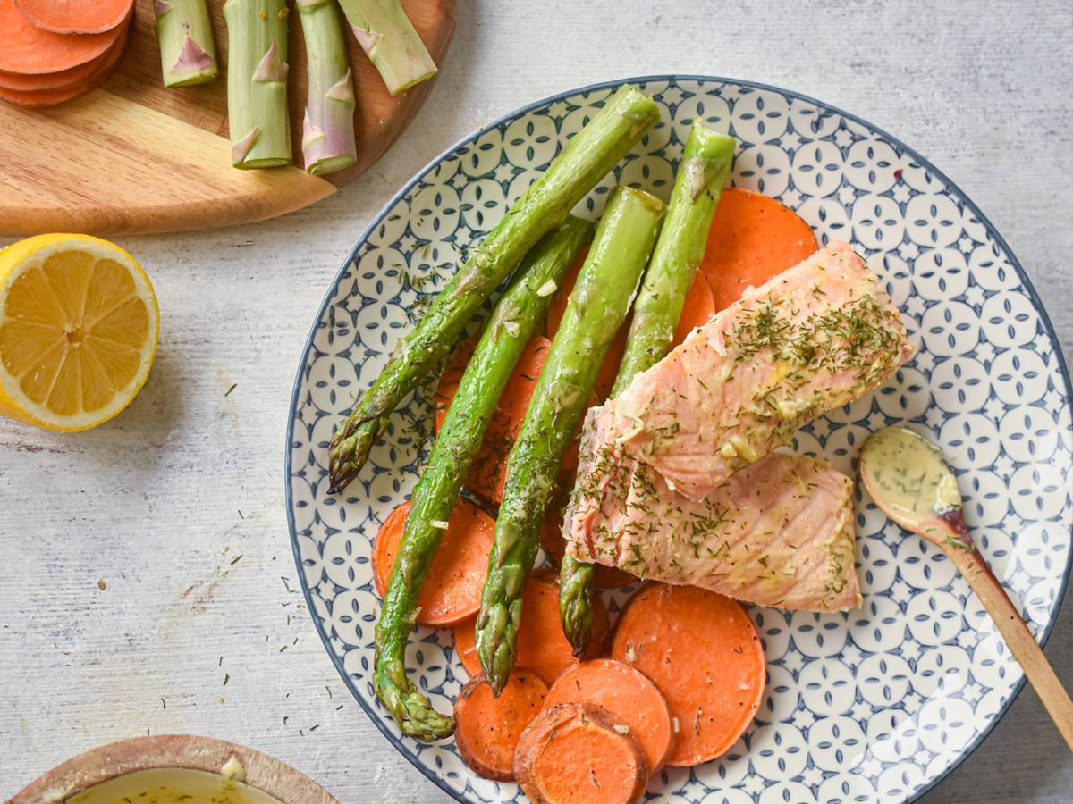 Sheet pan roasted salmon with sweet potatoes and asparagus on a plate with lemon Dijon sauce.